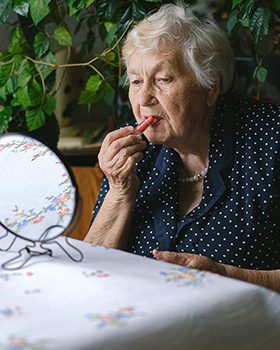 ältere Dame, die Lippenstift aufträgt