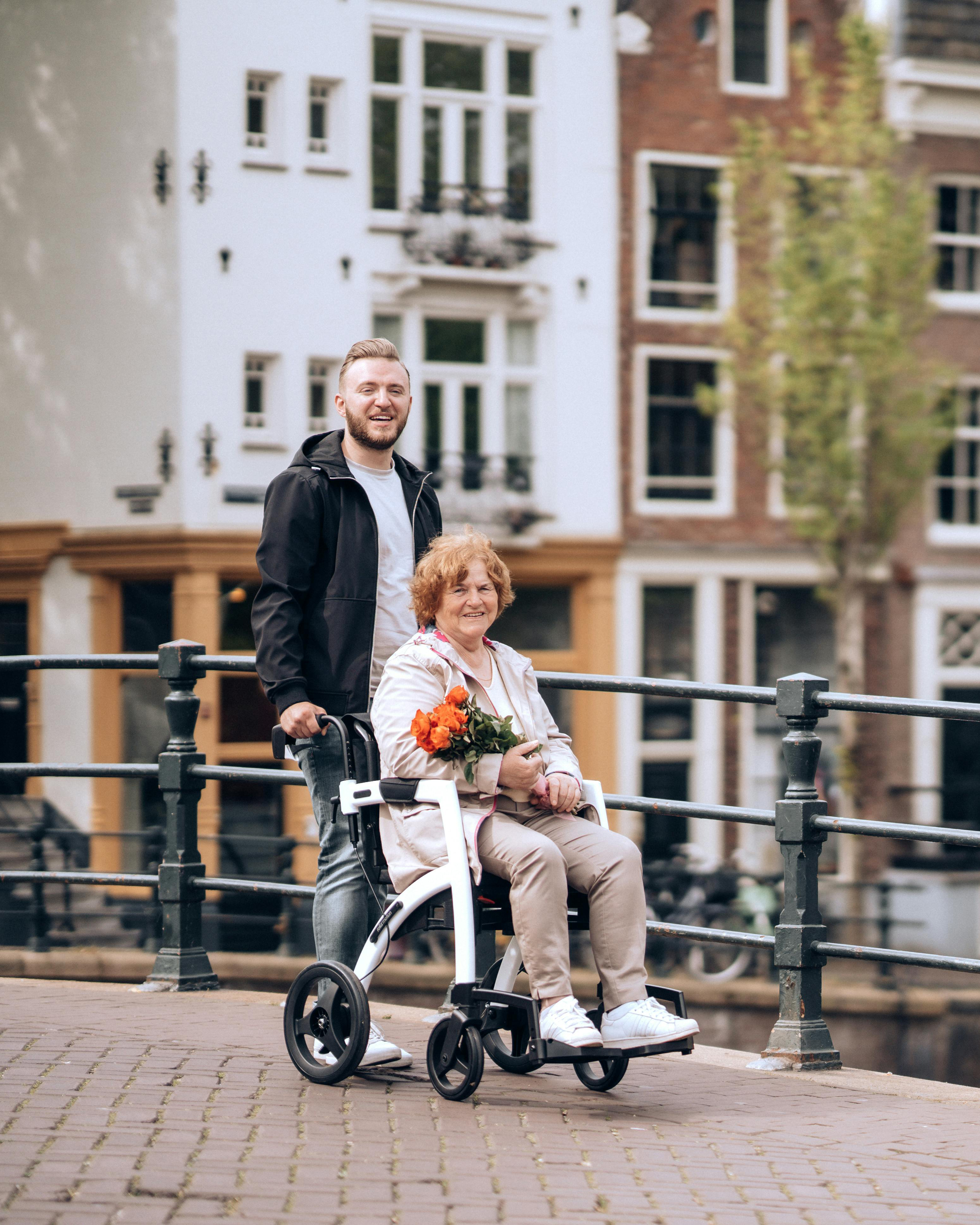 Junger Mann schiebt ältere Dame im Rollstuhl über die Straße